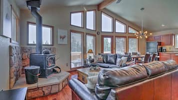 A cozy living room with a stone fireplace, leather sofa, and large windows.