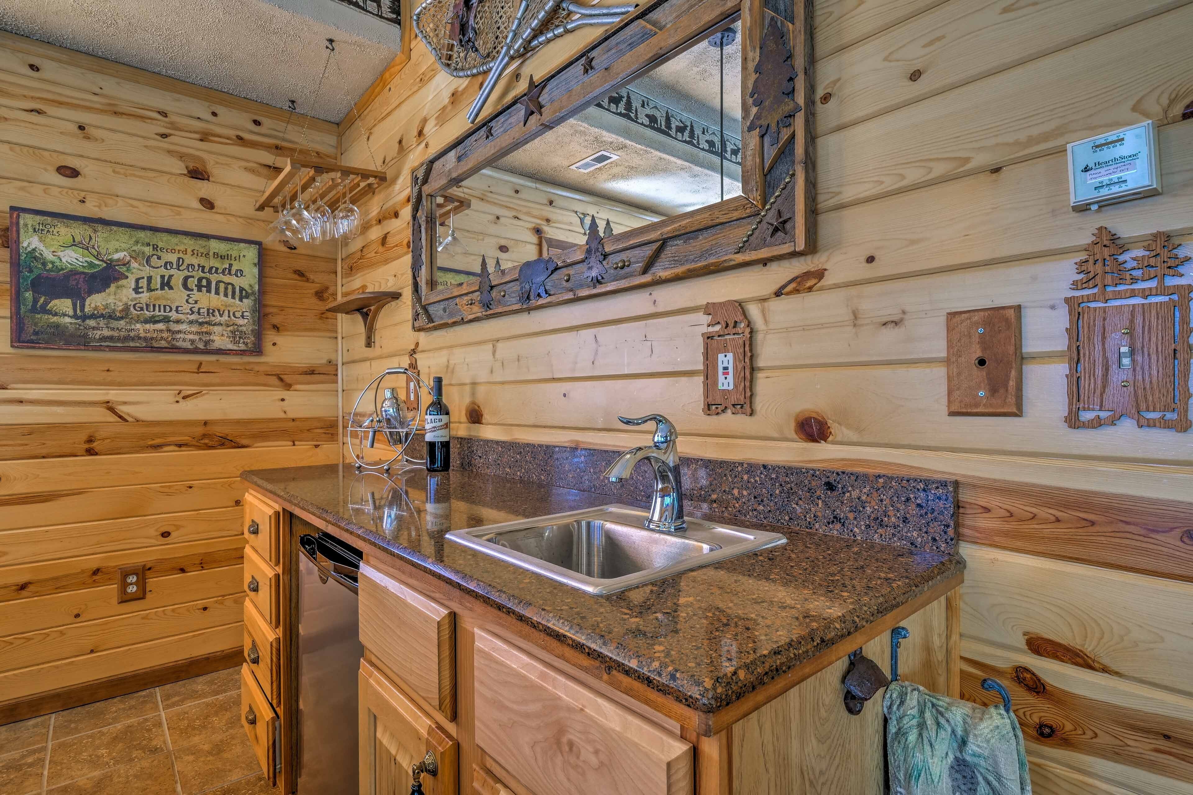 A wooden cabin interior with a granite countertop sink, wooden cabinets, and a large mirror reflecting the room.