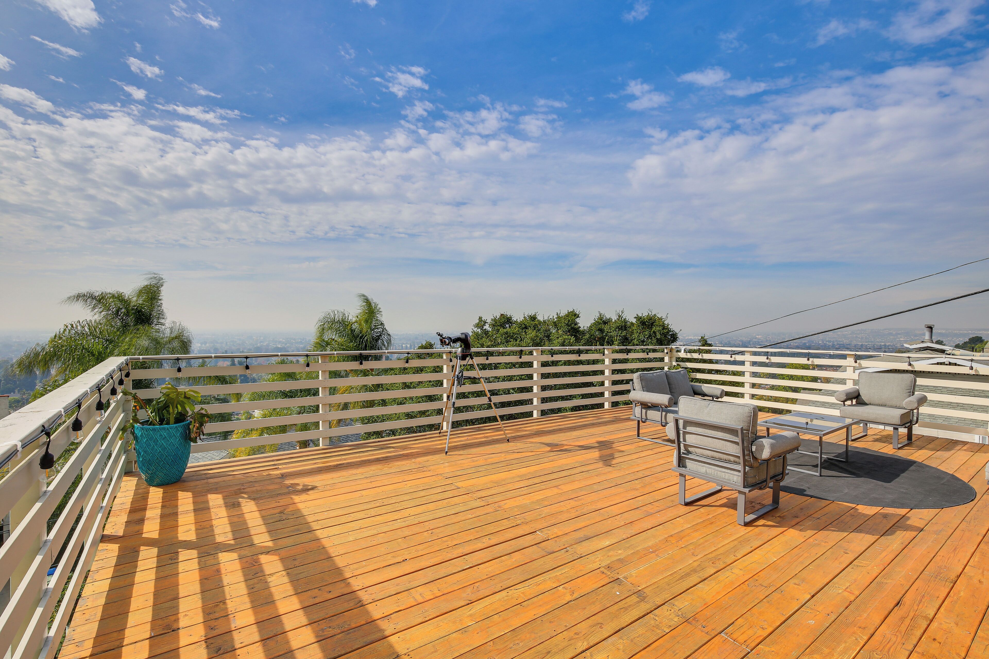 Eine Holzterrasse mit Gartenmöbeln und Geländer mit Blick auf eine schöne Landschaft.