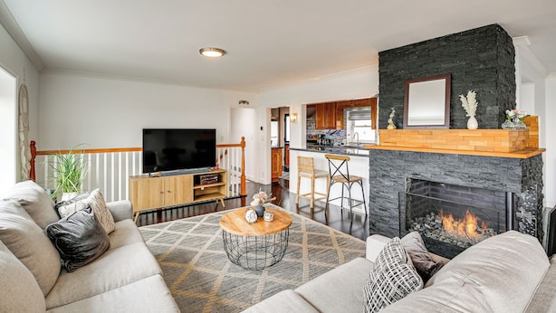 Een moderne woonkamer met een bank, een bijzettafeltje en een open haard.