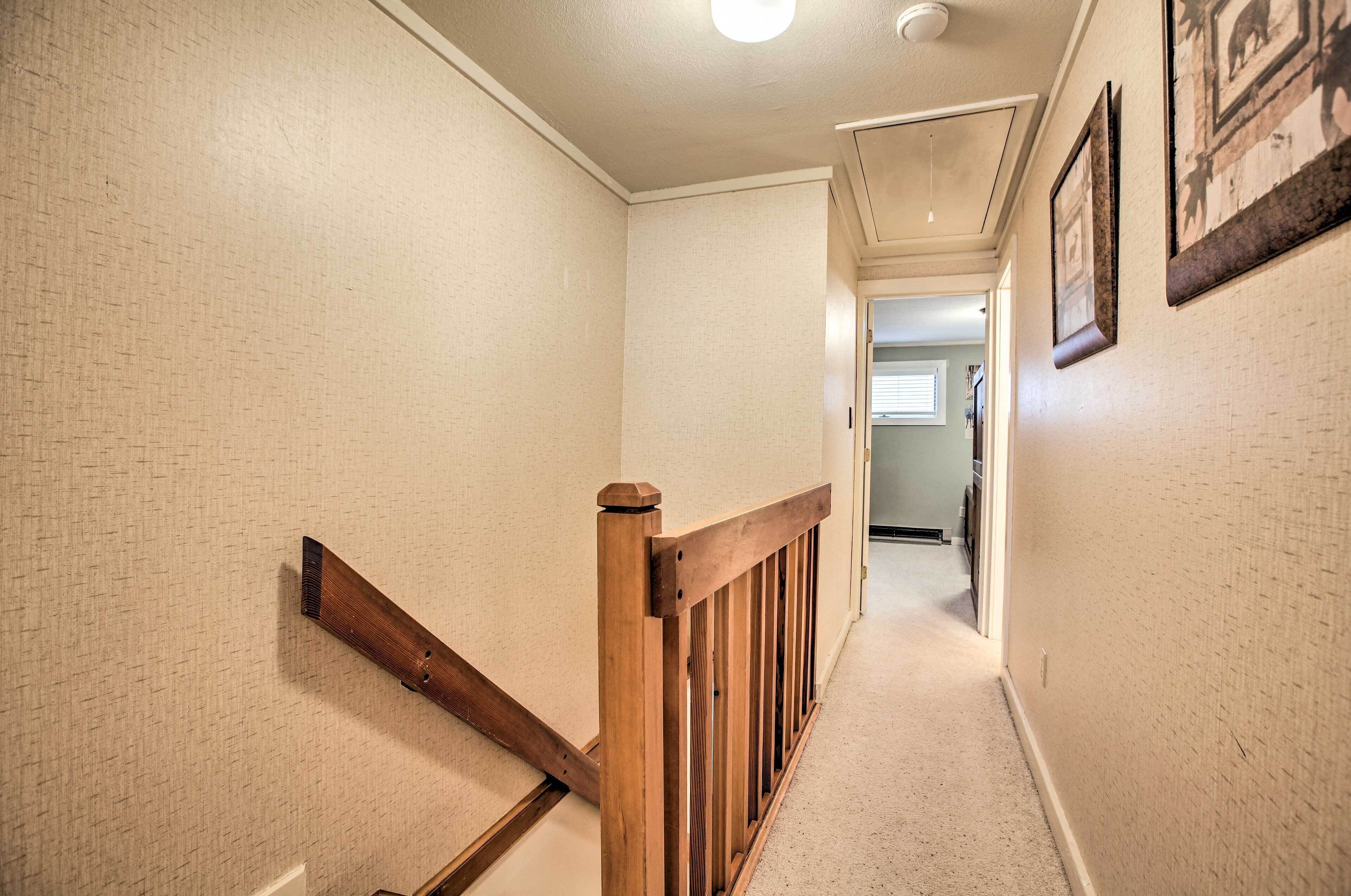 A hallway with beige textured walls, a wooden railing, and framed pictures on the wall.