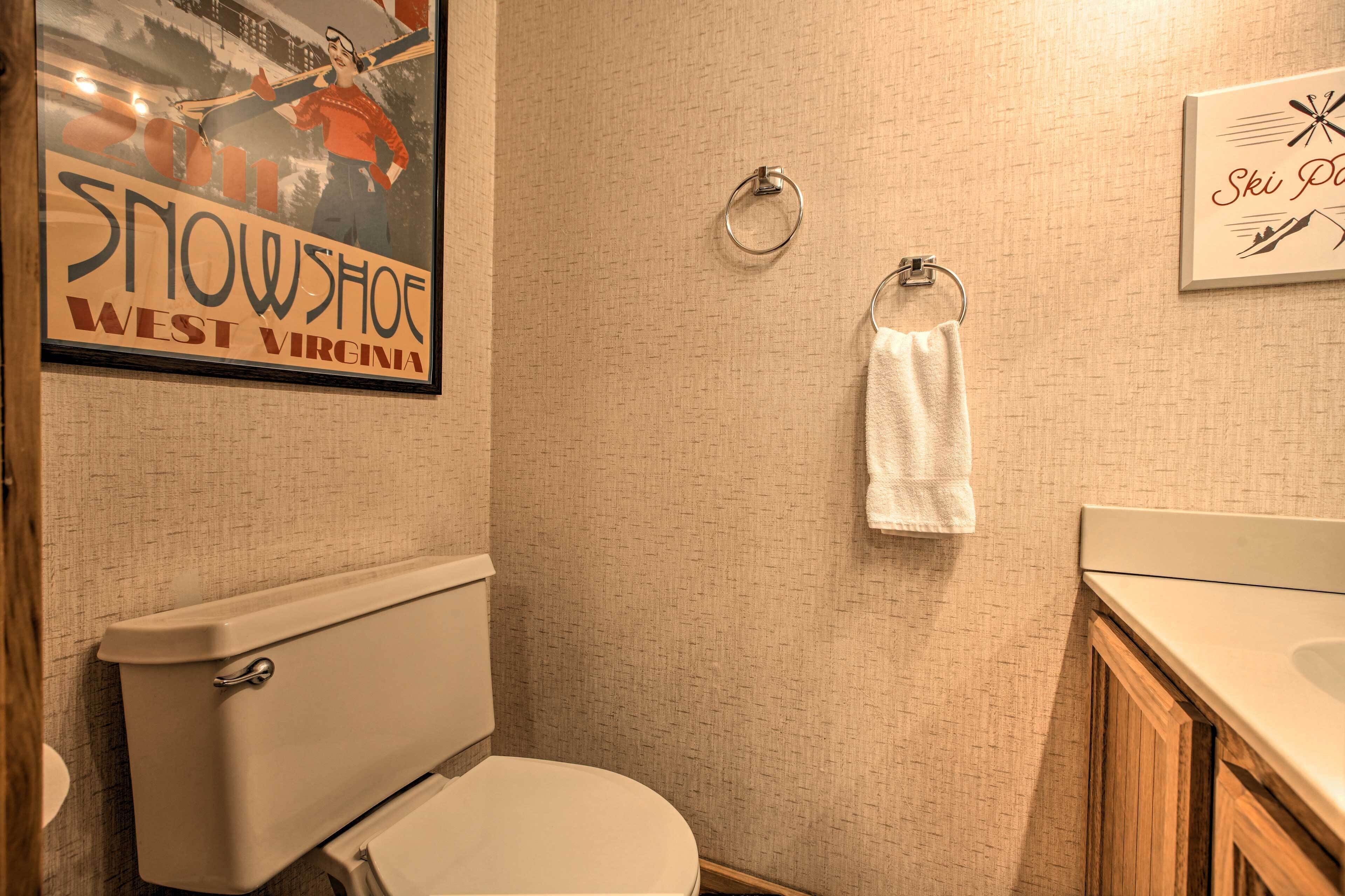A bathroom with a toilet, a towel ring, and a framed sign on the wall.