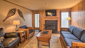 Una sala de estar acogedora con chimenea, muebles de cuero y un televisor de pantalla plana.
