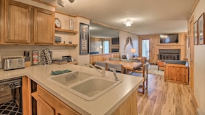 Una cocina con armarios de madera, un lavamanos y una zona de comedor con mesa y sillas.