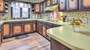 A kitchen with dark wooden cabinets, a yellow countertop, and a backsplash with a mosaic pattern.