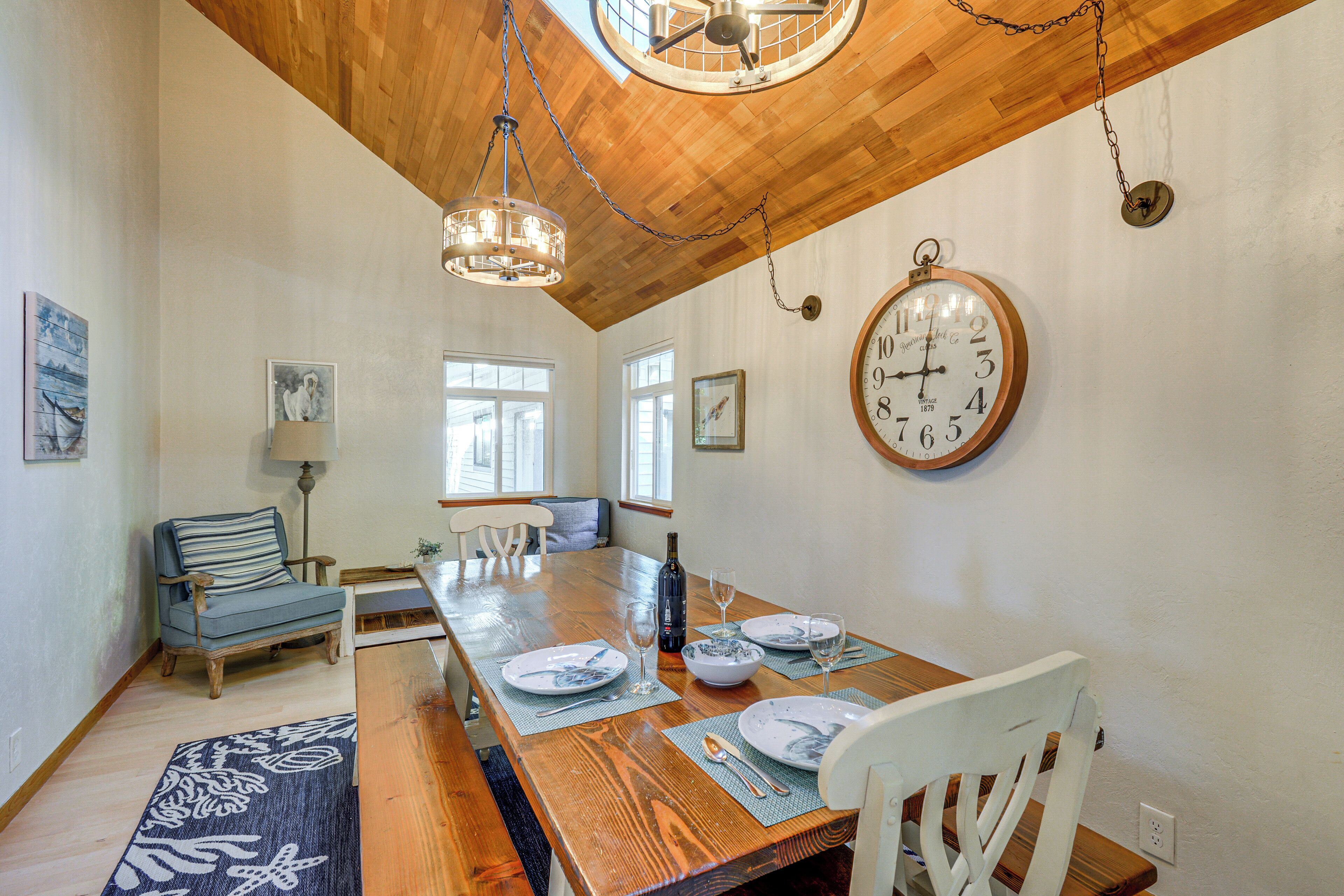 A dining room with a wooden table, chairs, and a large wall clock.