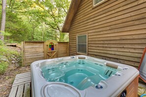Una cabaña de madera con un jacuzzi en el patio trasero.