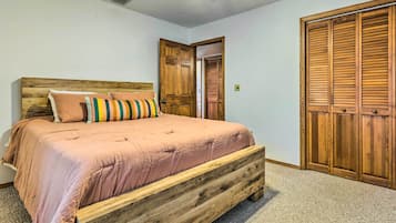 Un dormitorio con estructura de cama de madera, un armario grande y un ventilador de techo.