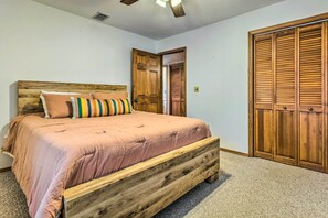 Un dormitorio con estructura de cama de madera, un armario grande y un ventilador de techo.