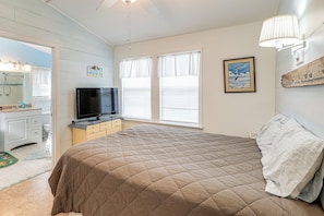 Un dormitorio con cama, televisión, cómoda y ventana con persianas.