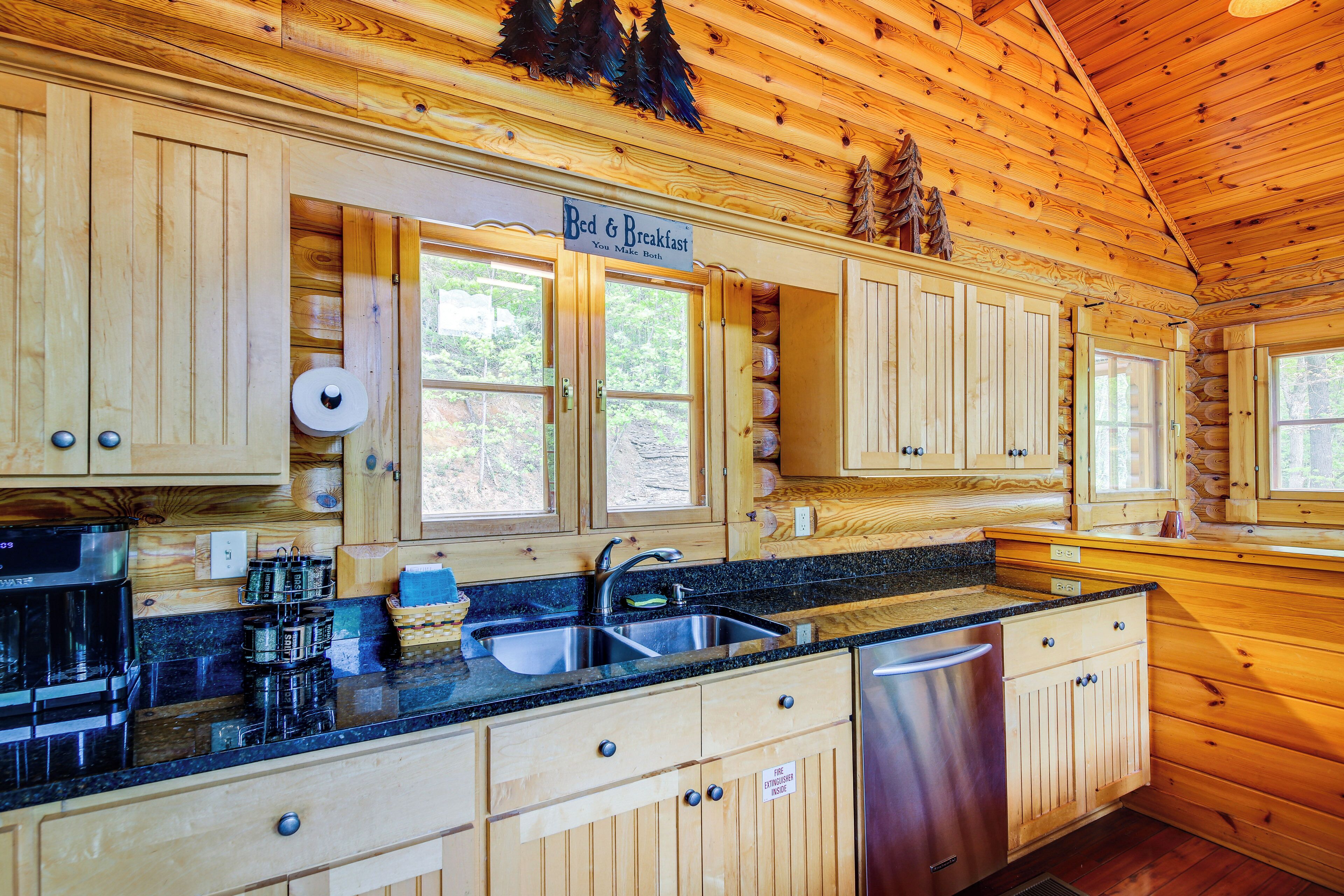 A wooden cabin interior with a kitchen featuring wooden cabinets, a black countertop, and a sign reading "Bed & Breakfast".