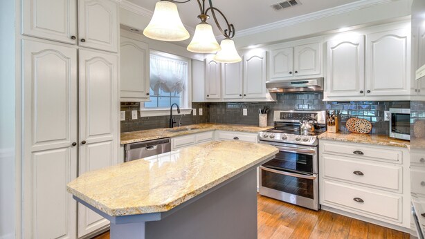 A kitchen with white cabinetry, granite countertops, stainless steel appliances, and pendant lighting. - Peaceful Fairhope Cottage w/ Covered Patio! (Fairhope)