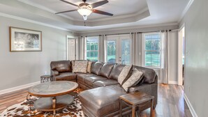 A spacious living room with a large sectional sofa, a round coffee table, and a ceiling fan. - Peaceful Fairhope Cottage w/ Covered Patio! (Fairhope)