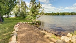 A lakeside camping area with a dirt path, surrounded by rocks and trees. - Thunder Lake Escape + Boat Dock! (Remer)