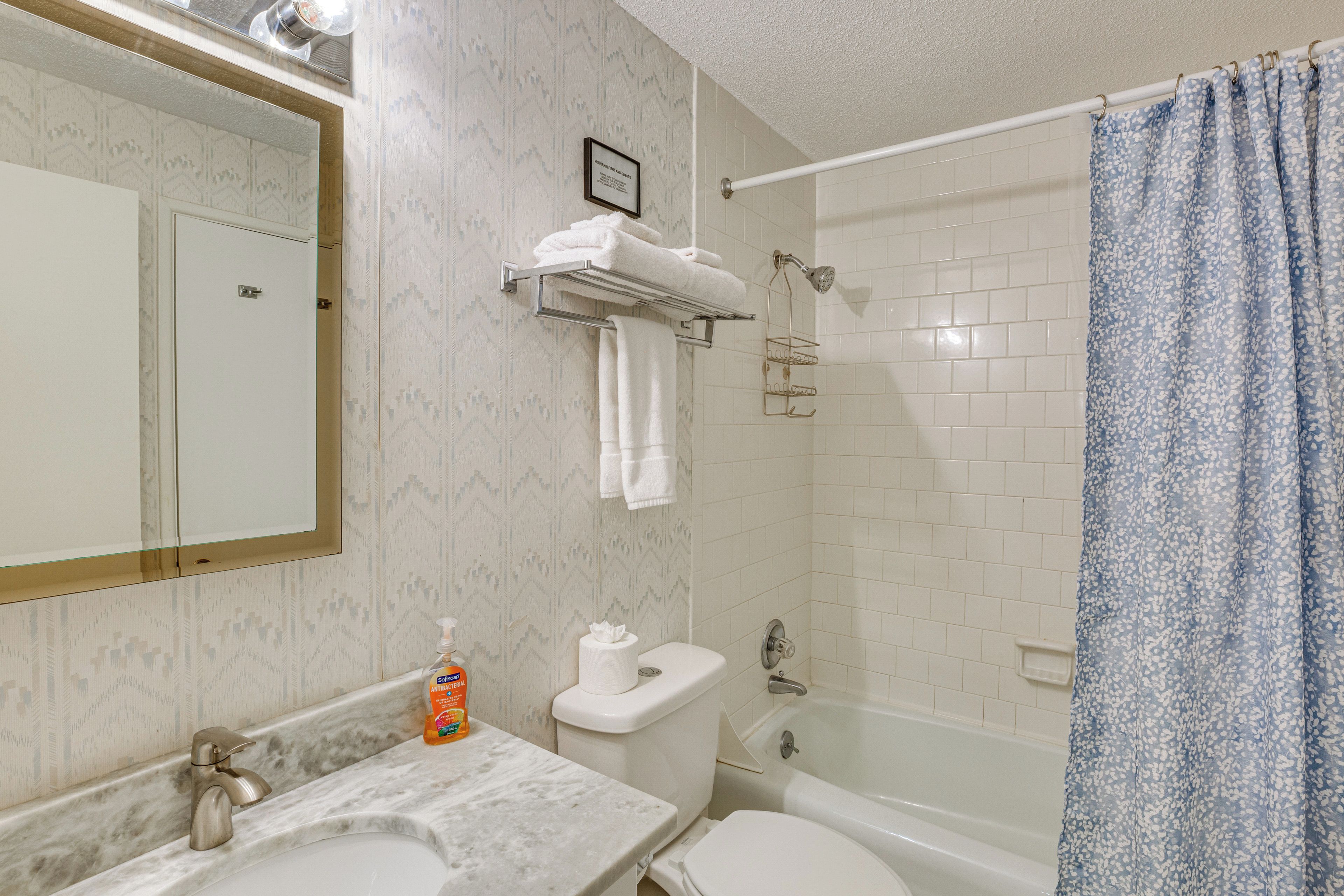 Une salle de bain avec un lavabo en marbre, des toilettes, une baignoire et un rideau de douche.