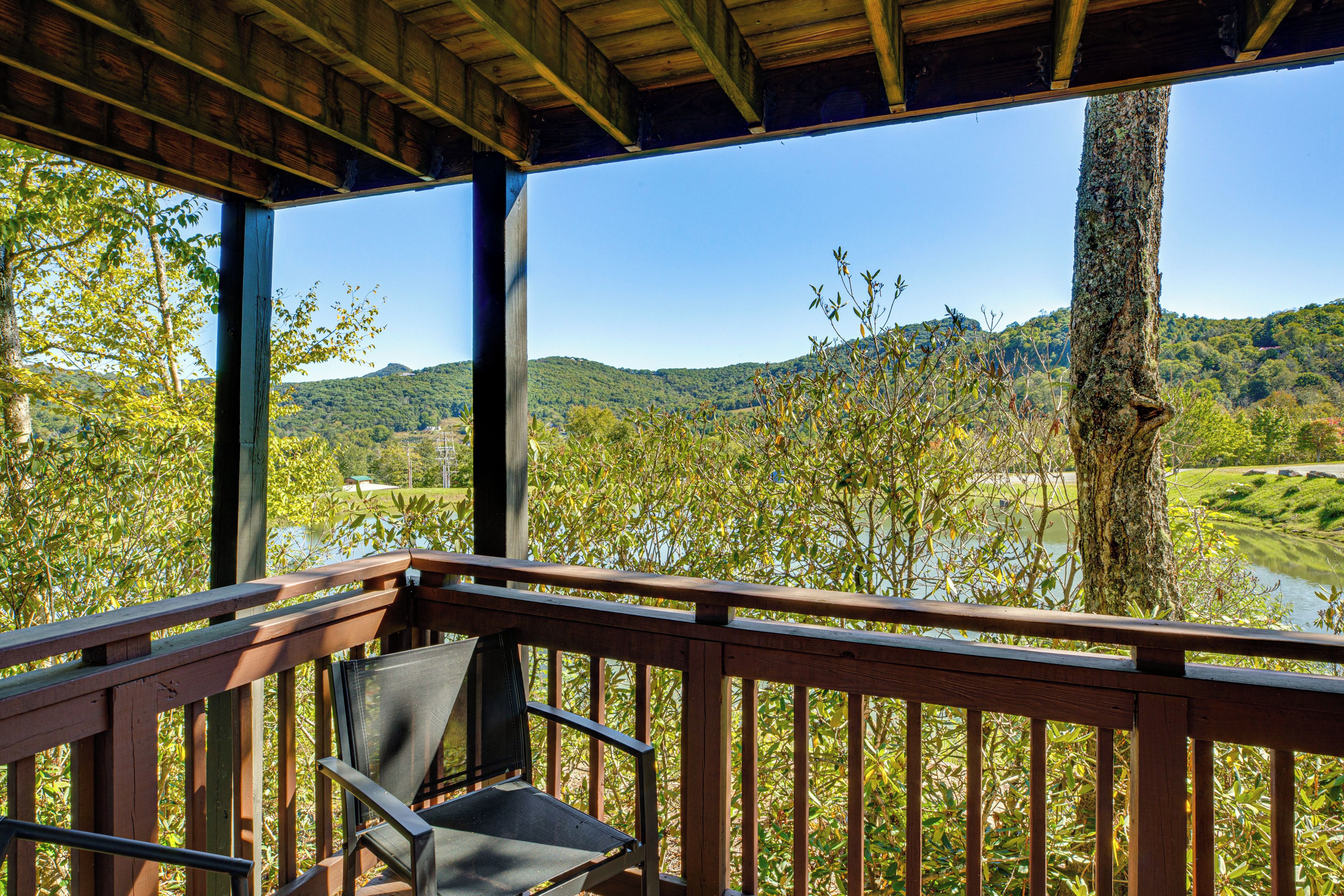 Une terrasse en bois avec un banc donnant sur une rivière et des collines.