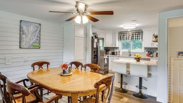 A kitchen with a dining table, chairs, a ceiling fan, and a refrigerator.