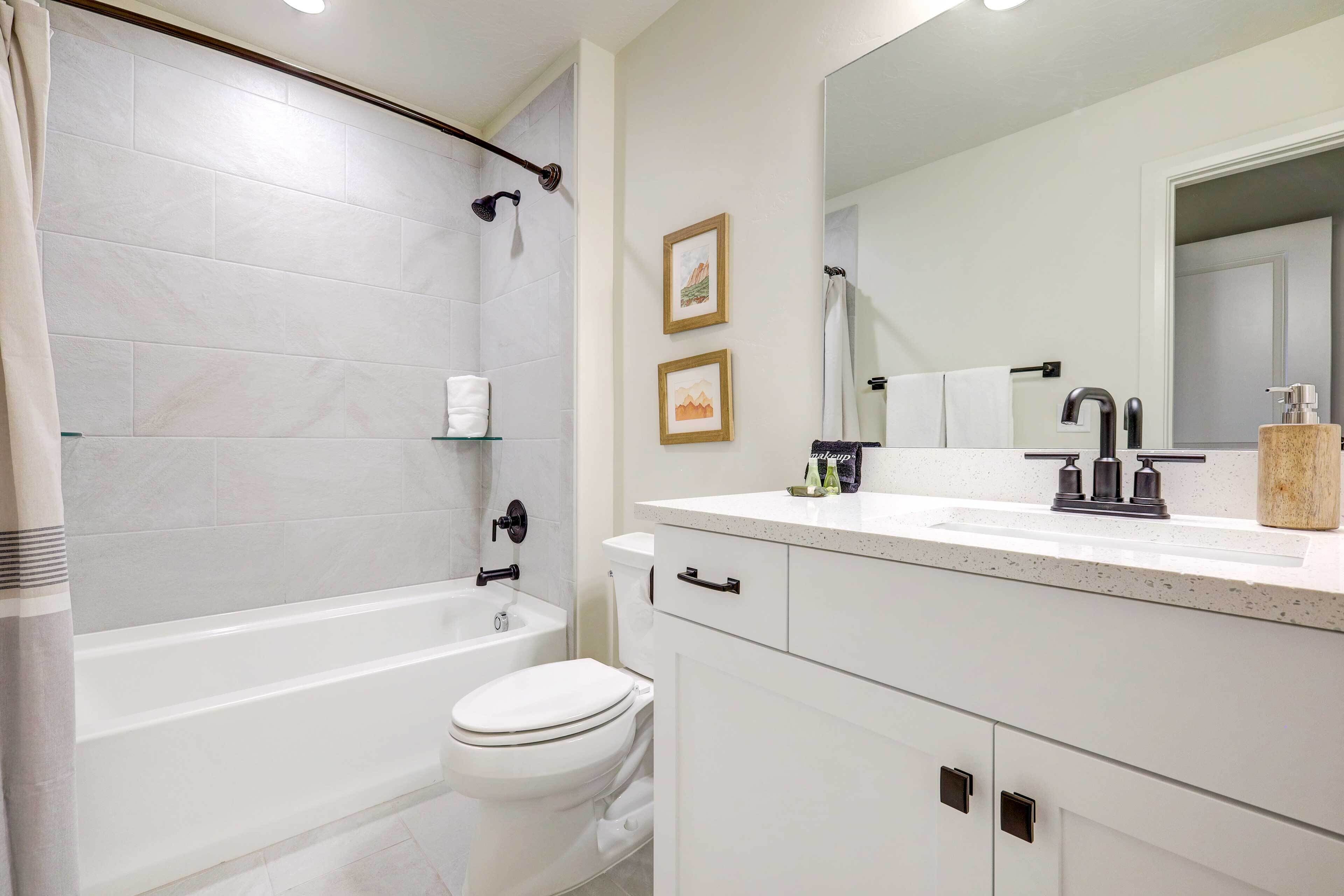 Een moderne badkamer met een bad, toilet en wastafelmeubel met spiegel en wastafel.