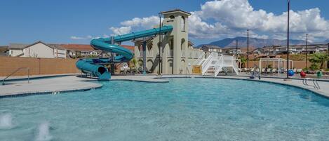 A swimming pool with a water slide and a tower structure in the background.