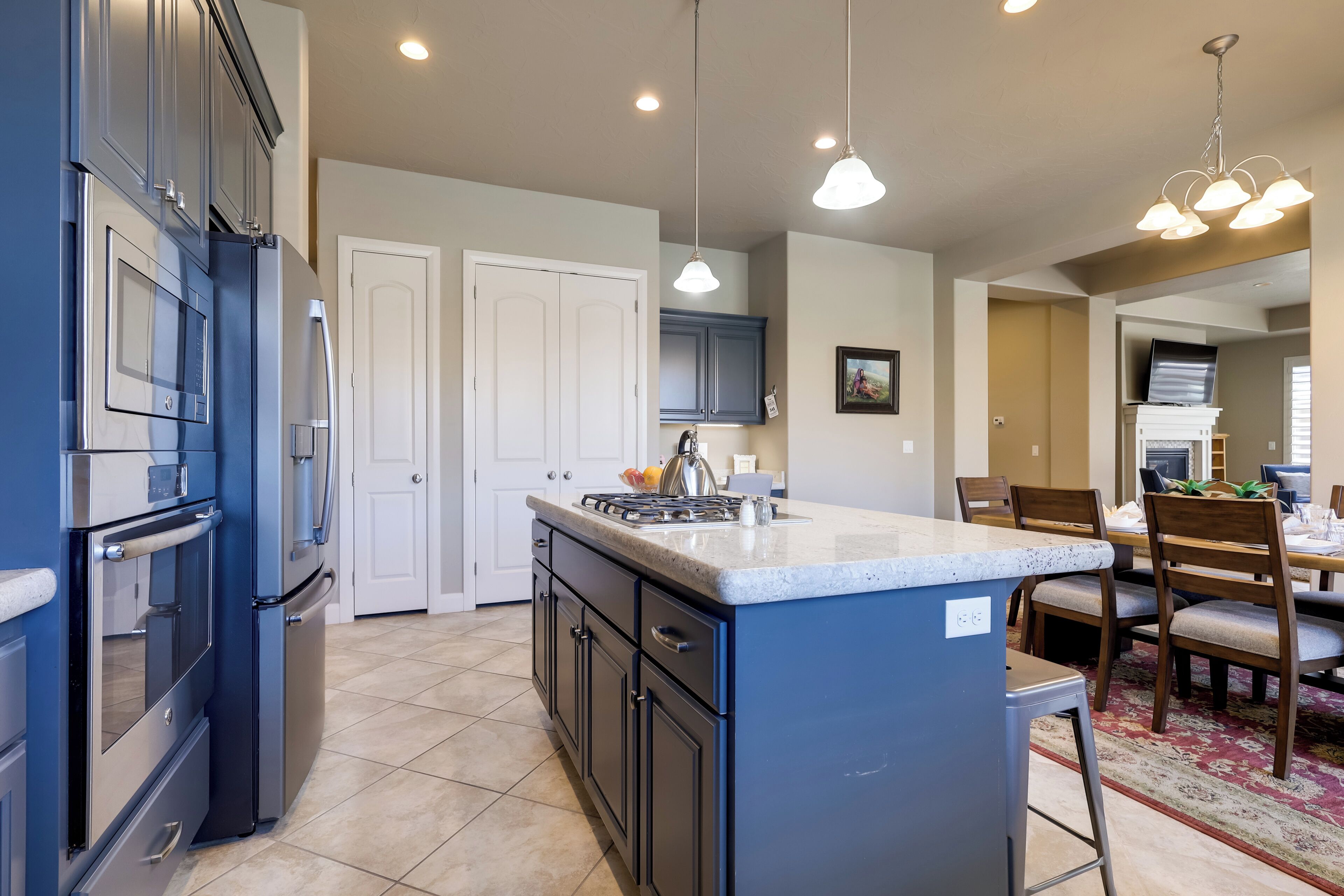 A modern kitchen with a central island, built-in appliances, and pendant lighting.