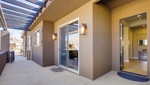Un espace extérieur abrité, doté d’une terrasse, de portes-fenêtres coulissantes et offrant une vue sur l’intérieur.
