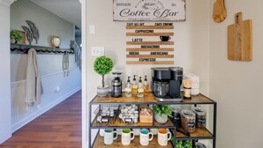Um café com um letreiro listando tipos de café, uma cafeteira e potes de armazenamento.