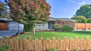 Stroll through the beautifully manicured lawn surrounded by mature trees and a charming wooden fence.