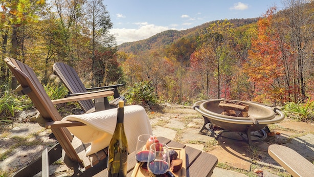 A wooden deck with a table set for a meal, a bottle of wine, and a fire pit. - Secluded Lenoir Cabin: 4 Mi to Dtwn Blowing Rock (Lenoir)