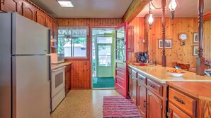 Une cuisine avec des meubles de rangement en bois, un réfrigérateur, un four à micro-ondes et un évier.