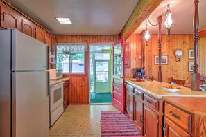 Una cocina con armarios de madera, un refrigerador, un microondas y un lavamanos.