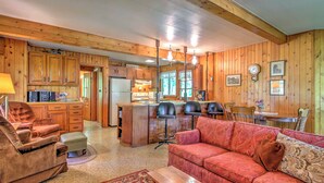 Un intérieur de chalet chaleureux comprenant un salon, une cuisine et un coin repas.
