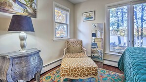 A bedroom with a bed, a chair, a lamp, and a painting on the wall.