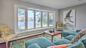 A living room with a large window, a sofa, a chair, and a table.