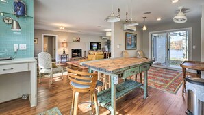 A spacious kitchen with a large wooden table, bar stools, and pendant lighting.
