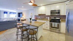 A modern kitchen with white cabinets, stainless steel appliances, and a central island with bar stools.