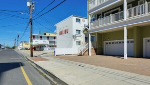 A multi-story hotel with a balcony on the second floor, a garage, and a clear sky.