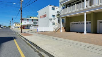 A multi-story hotel with a balcony on the second floor, a garage, and a clear sky.