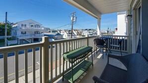 A balcony with a green bench, a table, and chairs.