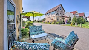 A patio with outdoor furniture and a green umbrella, a building with a red roof, and a clear sky. - Unique Townhouse in Bavarian-style Neighborhood! (Adamstown)