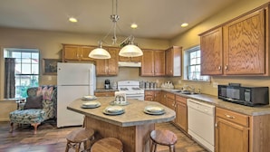 A kitchen with wooden cabinets, a central island with stools, a refrigerator, a microwave, and a dishwasher. - Unique Townhouse in Bavarian-style Neighborhood! (Adamstown)