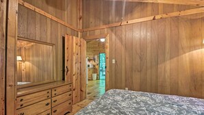 A wooden-paneled room with a bed, dresser, and a mirror. - Pisgah Forest 'the Oak' Cabin w/ Deck by Creek (Barnardsville)