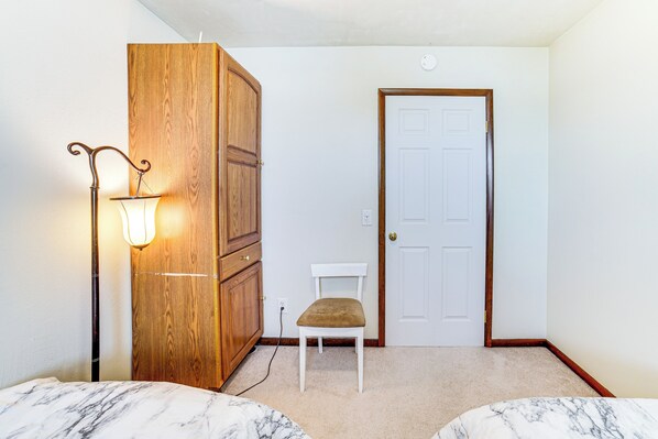 Un dormitorio con un armario de madera, una puerta blanca, una silla blanca y una lámpara.