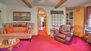 A living room with a checkered sofa, a leather armchair, and a wooden coffee table. - Wellington Cabin Escape w/ Wraparound Deck! (Wellington)