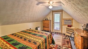 A cozy attic bedroom with a large bed, a wooden dresser, a desk, and a ceiling fan. - Wellington Cabin Escape w/ Wraparound Deck! (Wellington)