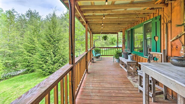 A wooden deck with a railing, a bench, and a table. - Wellington Cabin Escape w/ Wraparound Deck! (Wellington)