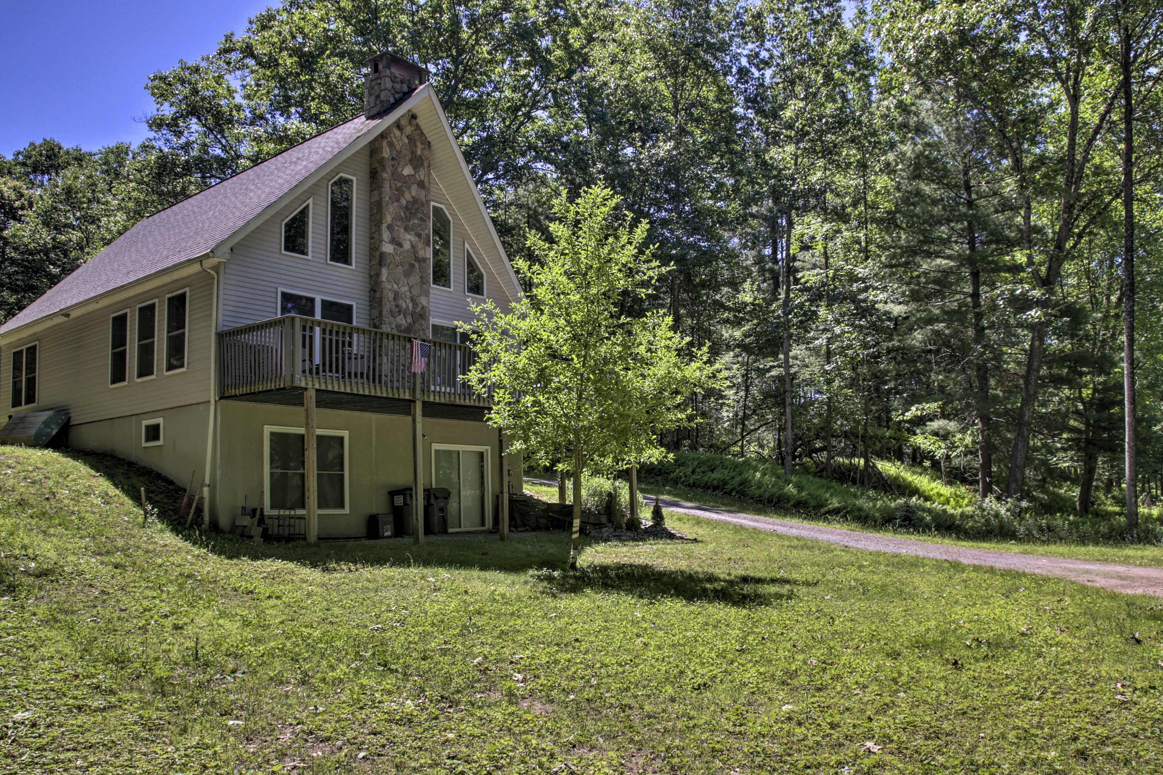 A two-story house with a stone chimney, a balcony, and a small porch.