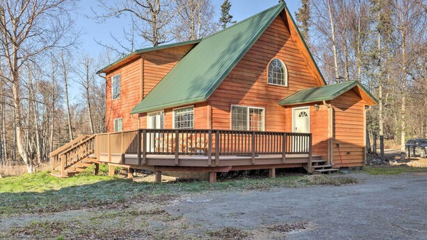 A wooden cabin with a green roof, a wooden deck, and a small attached shed. - Spacious & Private Home w/ Lazy Mountain View (Palmer)