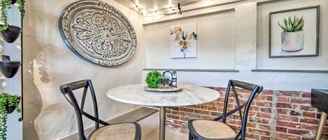 A cozy seating area with a round table, two chairs, a decorative plate, and string lights.