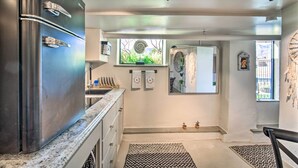 Een moderne keuken met een roestvrijstalen koelkast, granieten aanrechtbladen en een raam met uitzicht op groen.