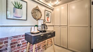 Een keuken met een bakstenen muur, een koffieapparaat, een lijst met spiegel en een kamerplant.